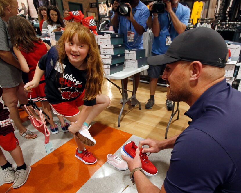 McKenzie Larock, 9, of Fort Worth, scurries to remove a shoe as Dallas Cowboys tight end...