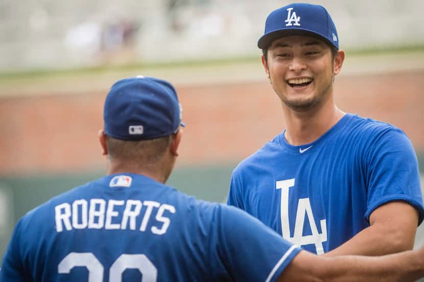 Los Angeles Dodgers' Yu Darvish, right, talks to manager Dave Roberts before a baseball game...
