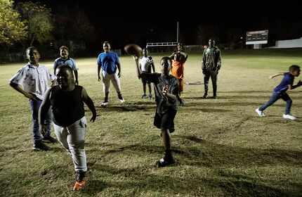 Javorian Simpson (center), 10, throws a pass on the football field at the Cedar Crest...