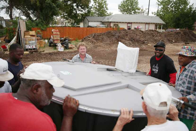 
Daron Babcock (top left) and other farm workers wrestled a donated 850-pound composting...