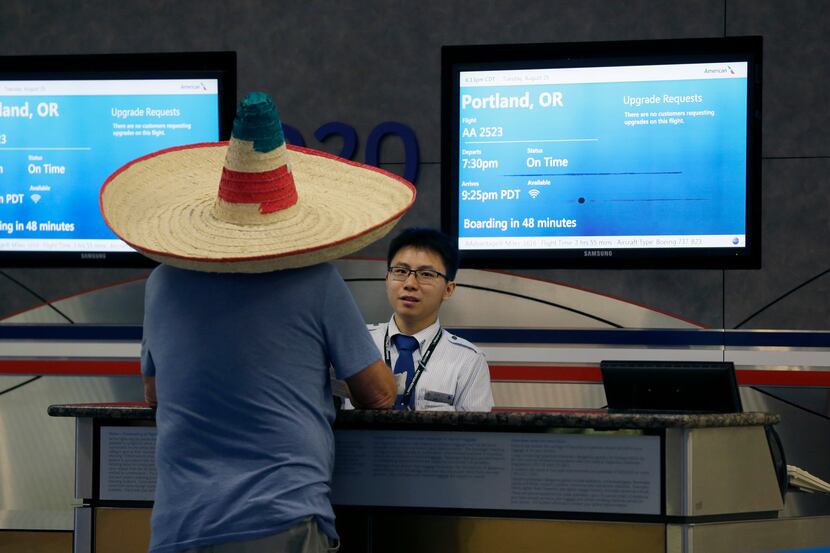 A passenger wearing a sombrero checks with a flight gate agent at Dallas/Fort Worth...