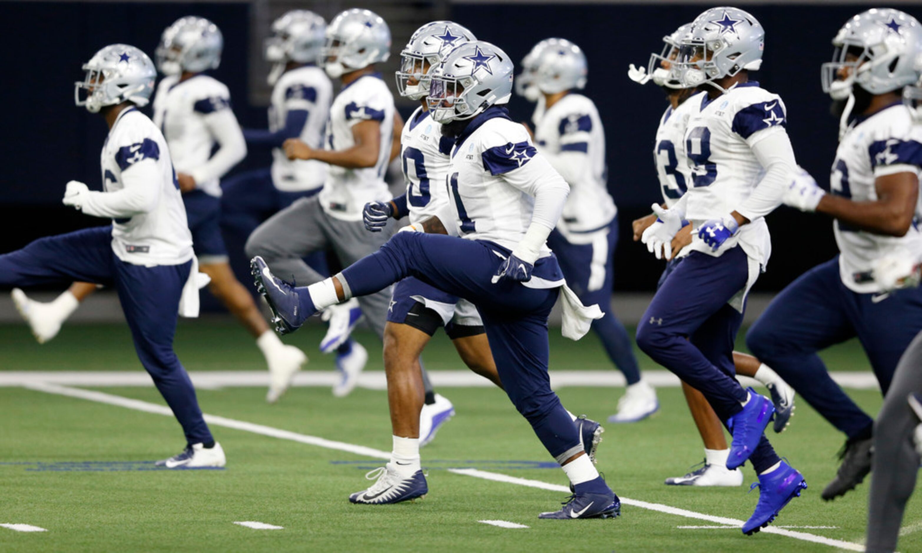 Dallas Cowboys running back Ezekiel Elliott (21) and teammates stretch during practice at...