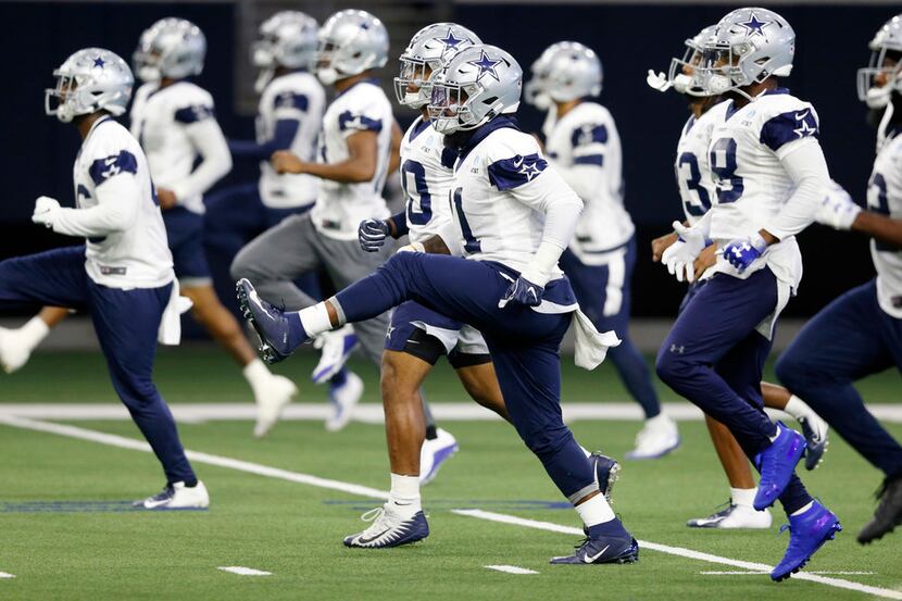 Dallas Cowboys running back Ezekiel Elliott (21) and teammates stretch during practice at...