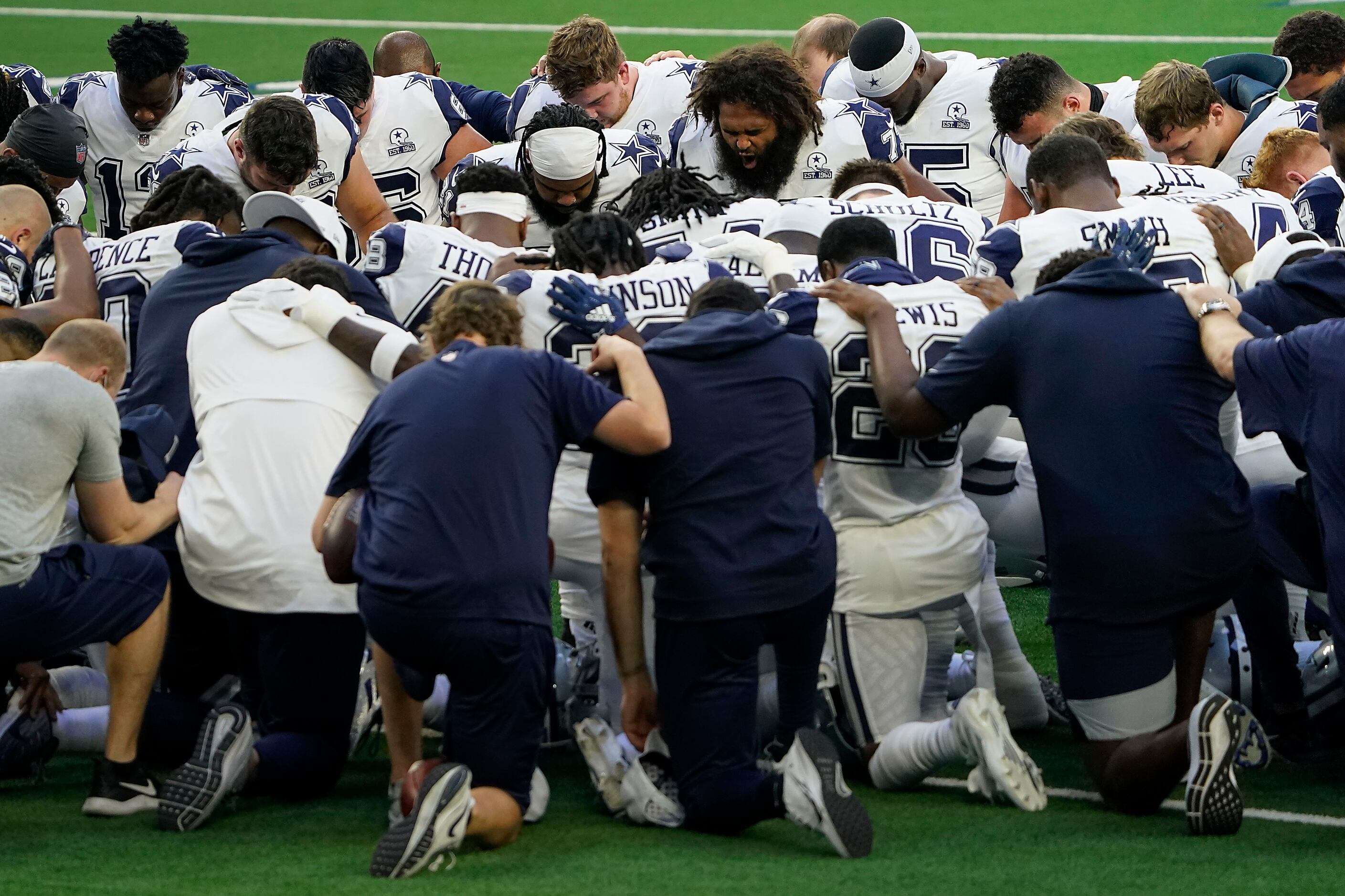 Dallas Cowboys players kneel around running back Ezekiel Elliott (facing left) and center...