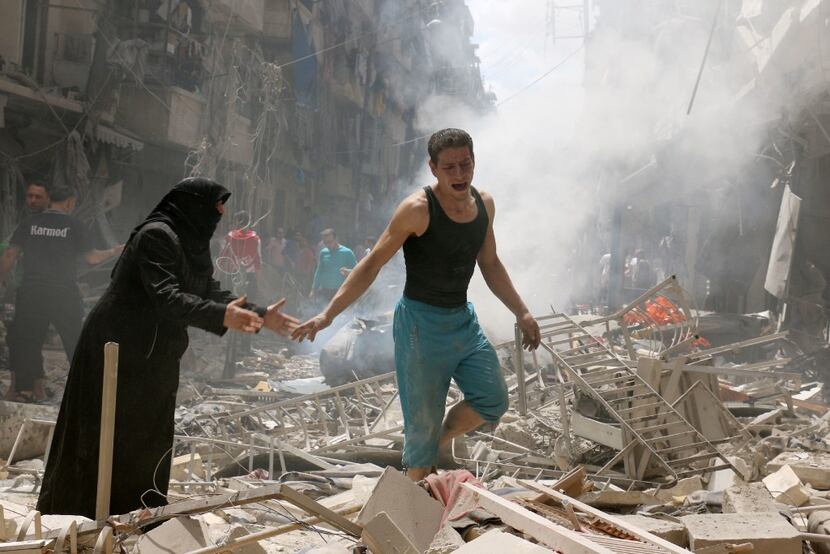 People walked amid the rubble of destroyed buildings following an airstrike on a rebel-held...