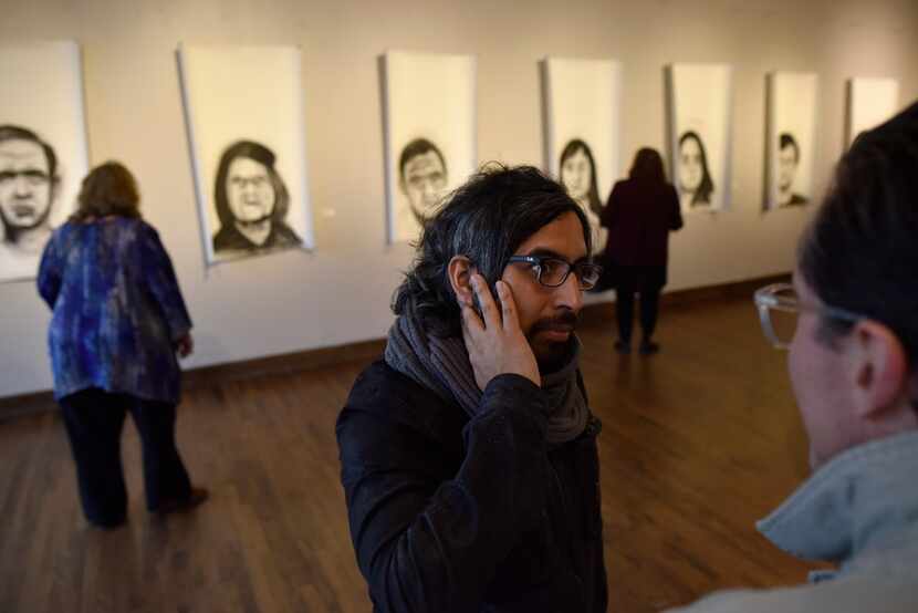 Peruvian artist Rudolph Castro (center) speaks with a visitor to his art exhibition at the...