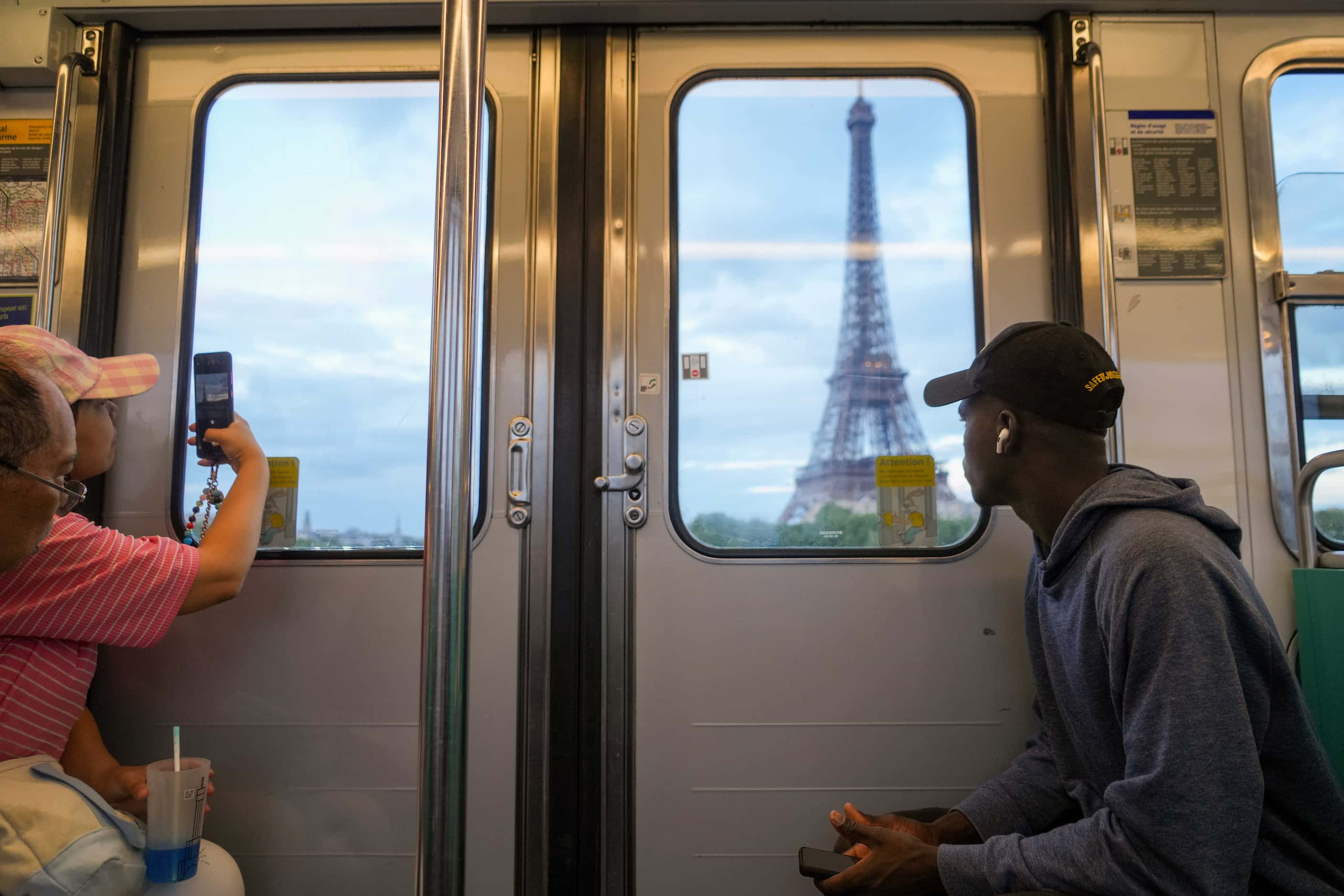 Riders look out toward the Eiffel Tower from a metro train ahead of the 2024 Summer Olympics...