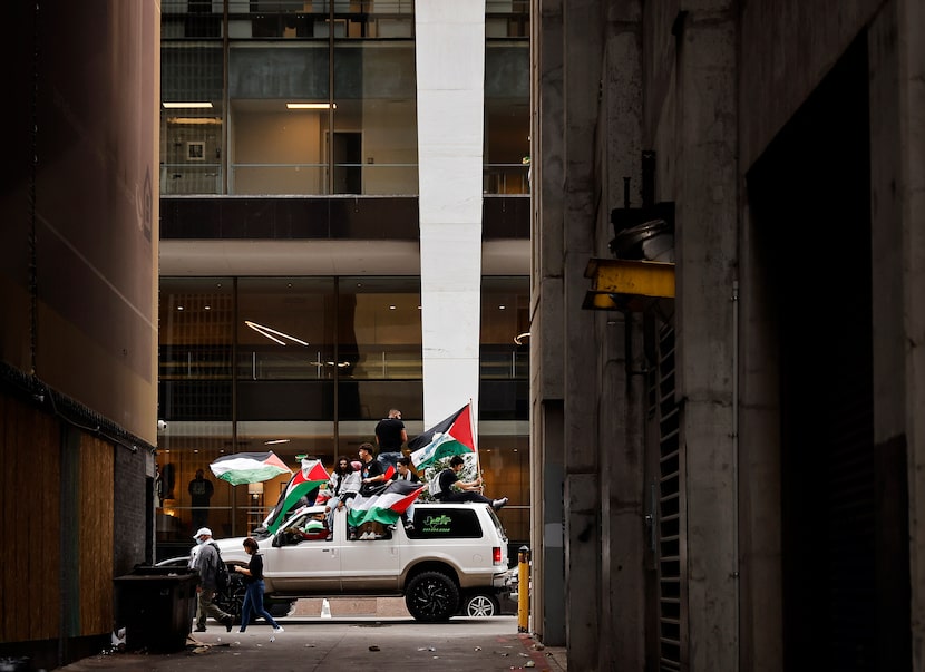 Truckloads of flag-waving demonstrators make their way down Elm Street.