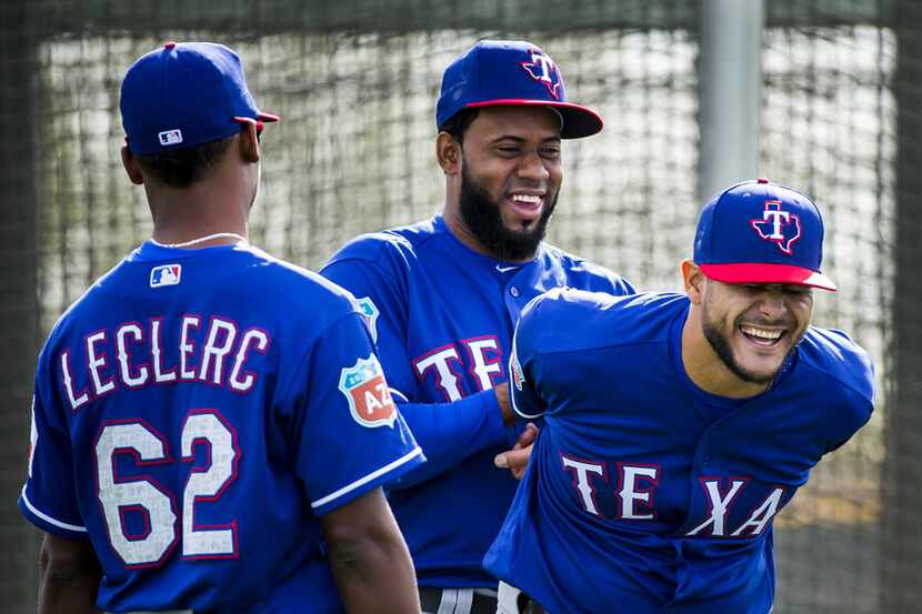 Texas Rangers pitcher Yohander Mendez helps Martin Perez stretch as Jose Leclerc looks on...