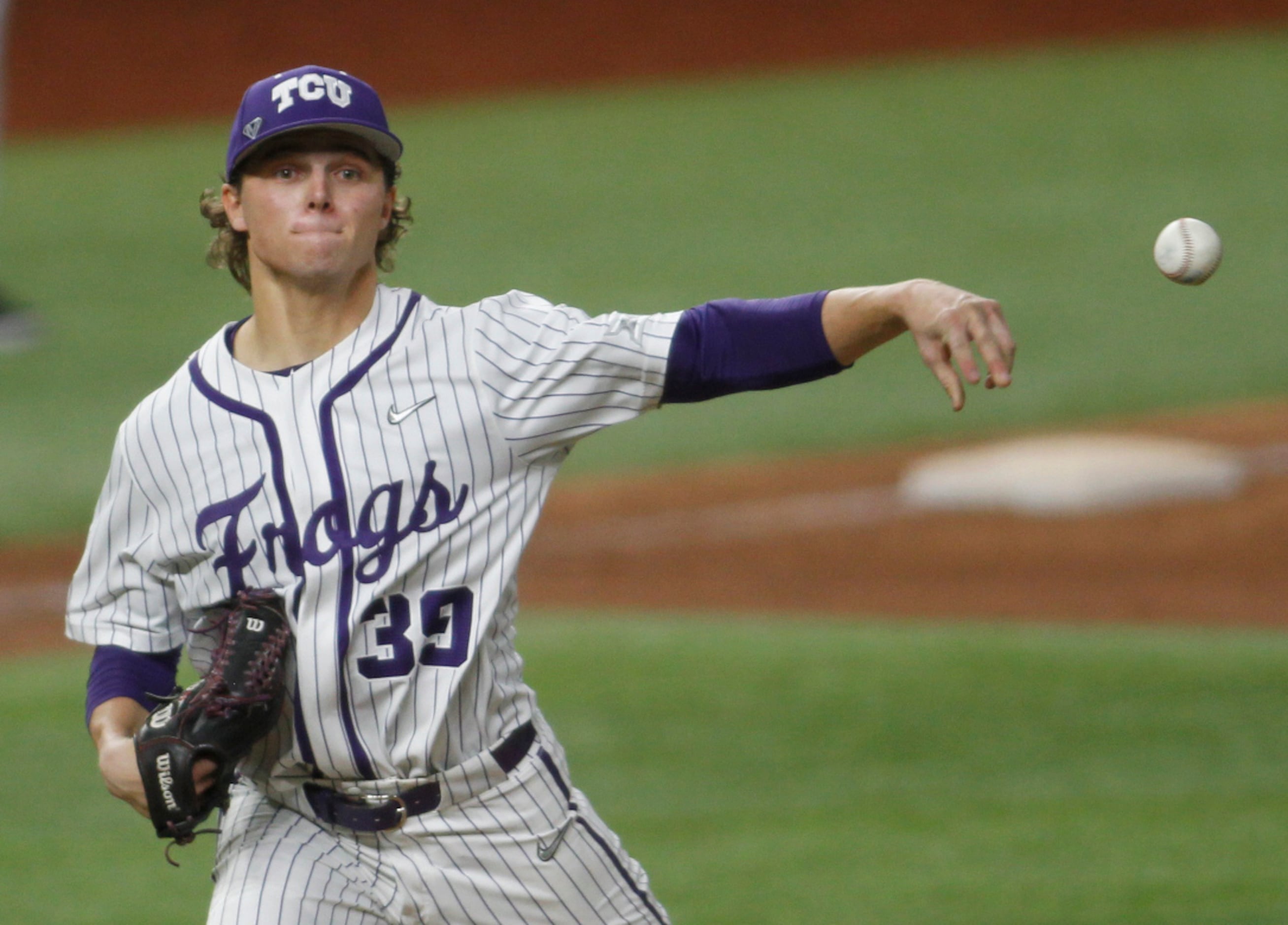 TCU pitcher Austin Krob spins and tosses to first base to keep an Arkansas base runner close...