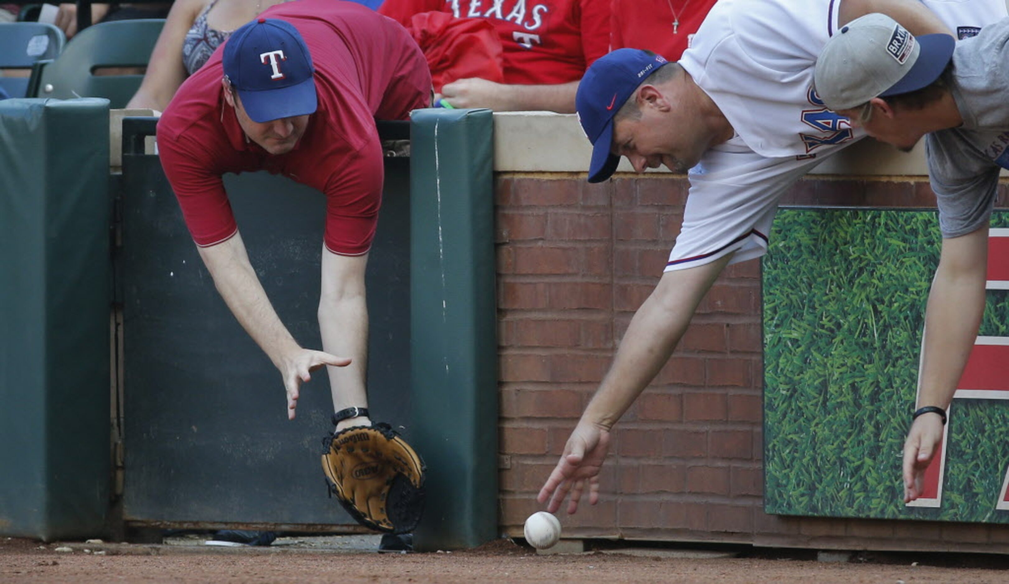 Baseball fame lean over the wall down the right field line to try and snag a foul ball in...