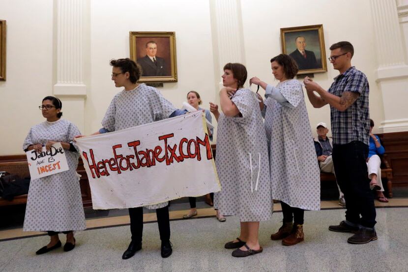  Activists tie on hospital gowns as they prepare to protest House Bill 3994 in the rotunda...