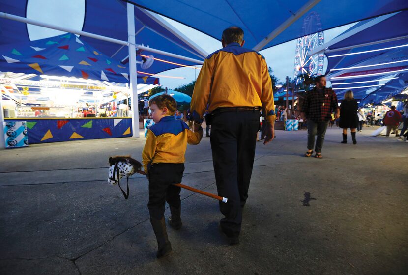 James Stephen La Due rides his stick horse as his dad, Stephen Ladue of Mansfield, guides...