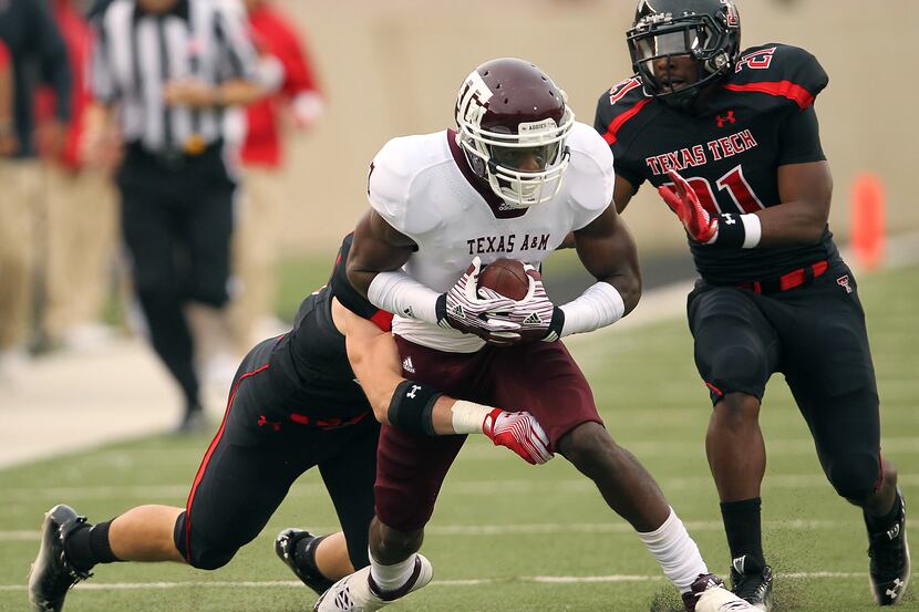 Texas A&M's Uzoma Nwachukwu, center, tries to get past Texas Tech's Cody Davis, left, and...