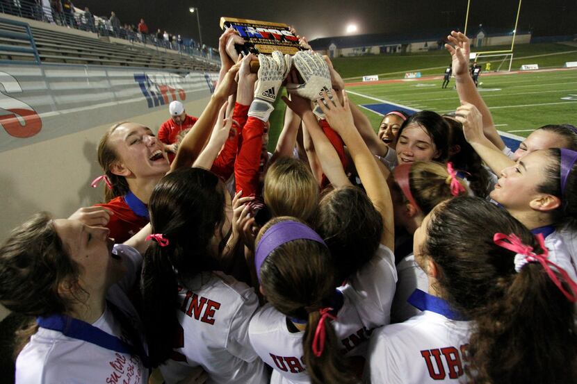 Ursuline players stretch to reach the state championship trophy they were awarded following...