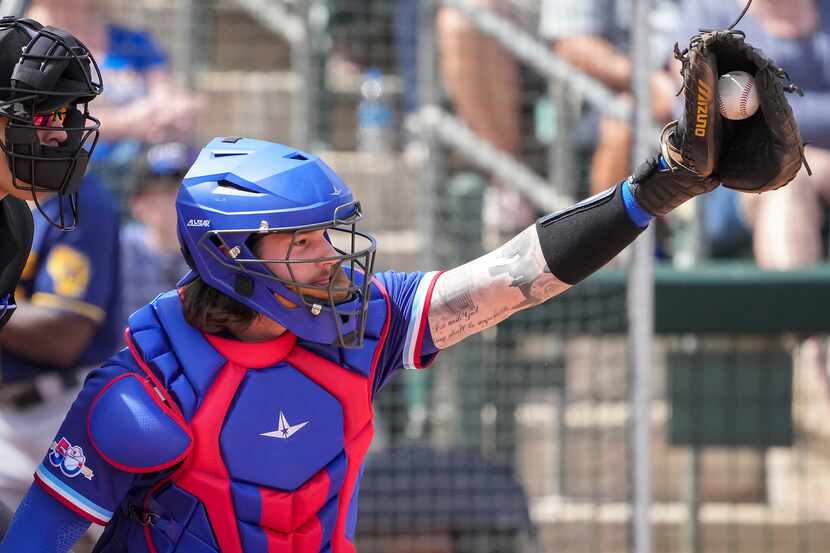 Texas Rangers catcher Jonah Heim works behind the plate during a spring training game...
