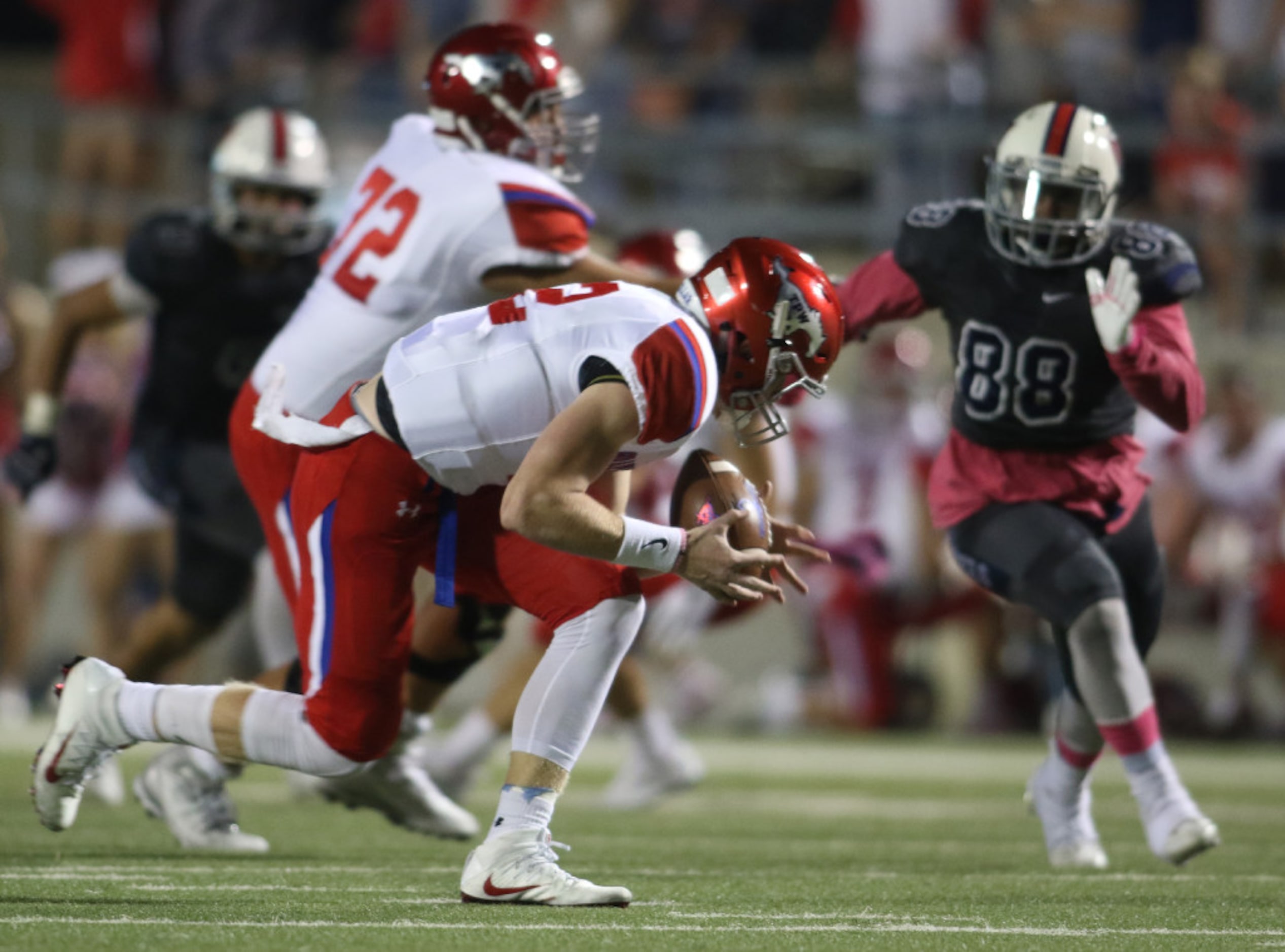 Grapevine quarterback Alan Bowman (12) cradles the ball after scooping low to field a high...