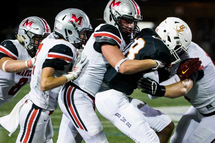 Arlington Bowie wide receiver Jimmy Valsin (18) is tackled by Flower Mound Marcus defenders...