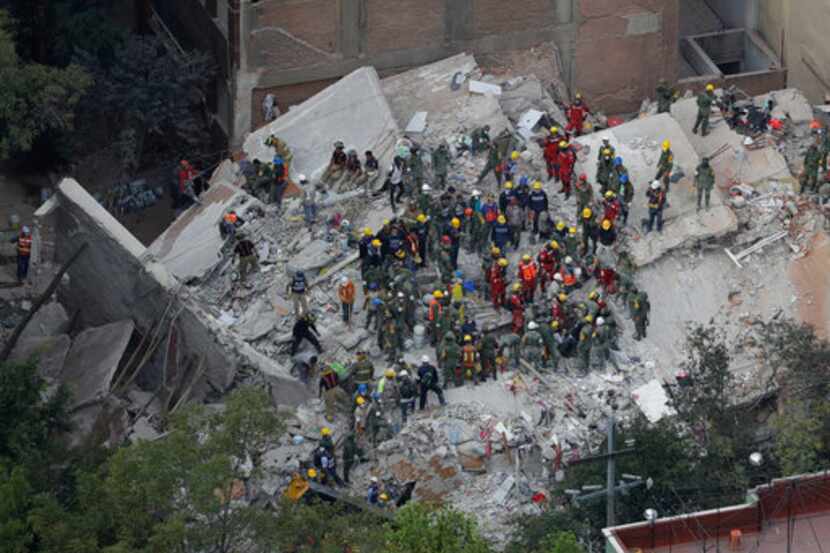 Unos rescatistas buscan personas que podrían estar atrapadas en un edificio que se derrumbó...