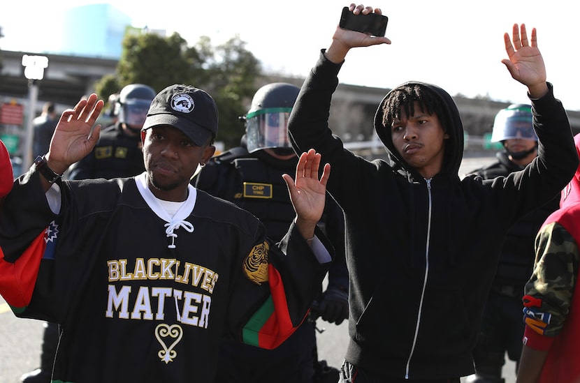  Black Lives Matter protesters stand with their hands up in front of California Highway...