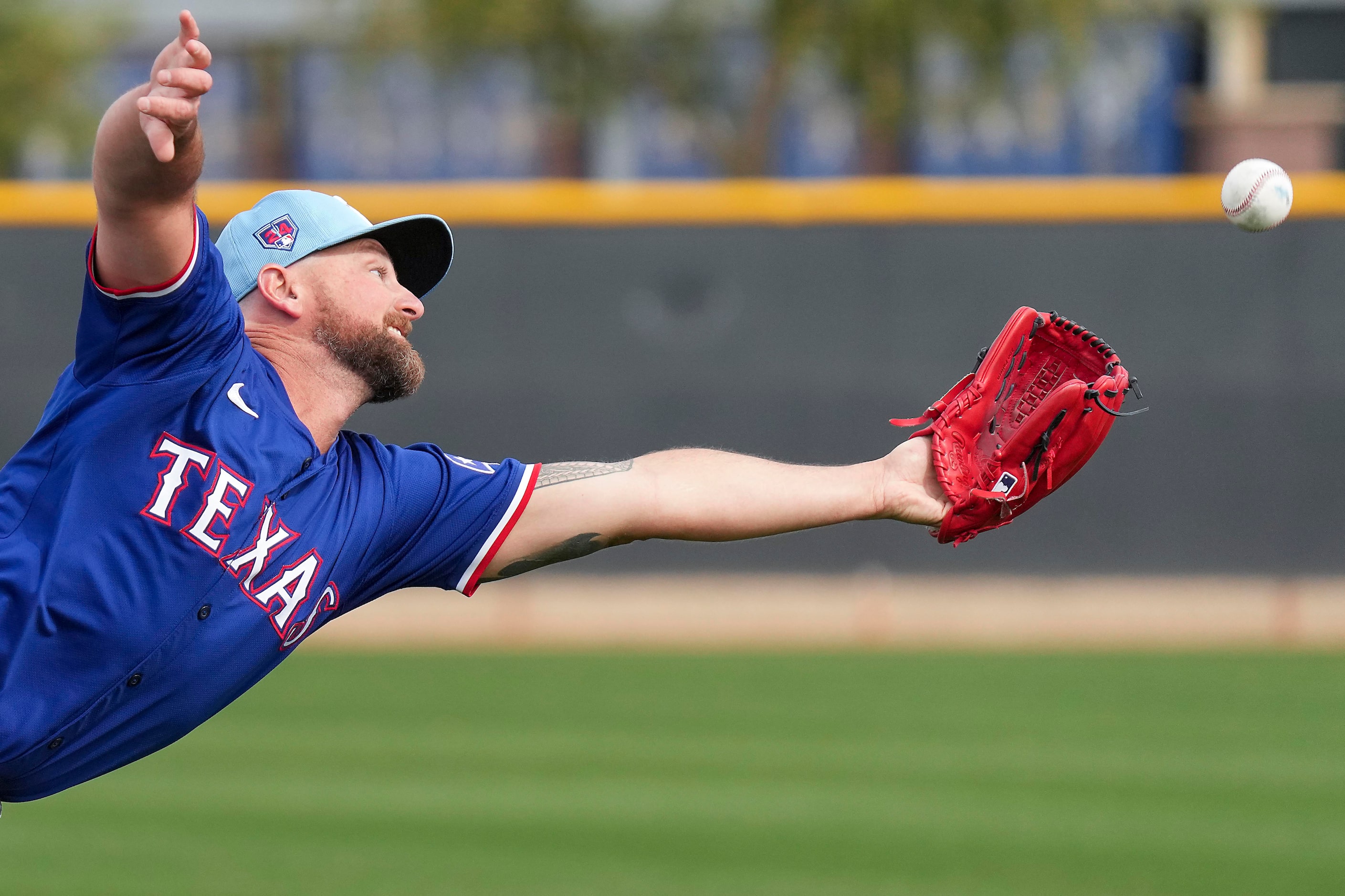 Texas Rangers pitcher Kirby Yates dives for a popup in a fielding drill during a spring...