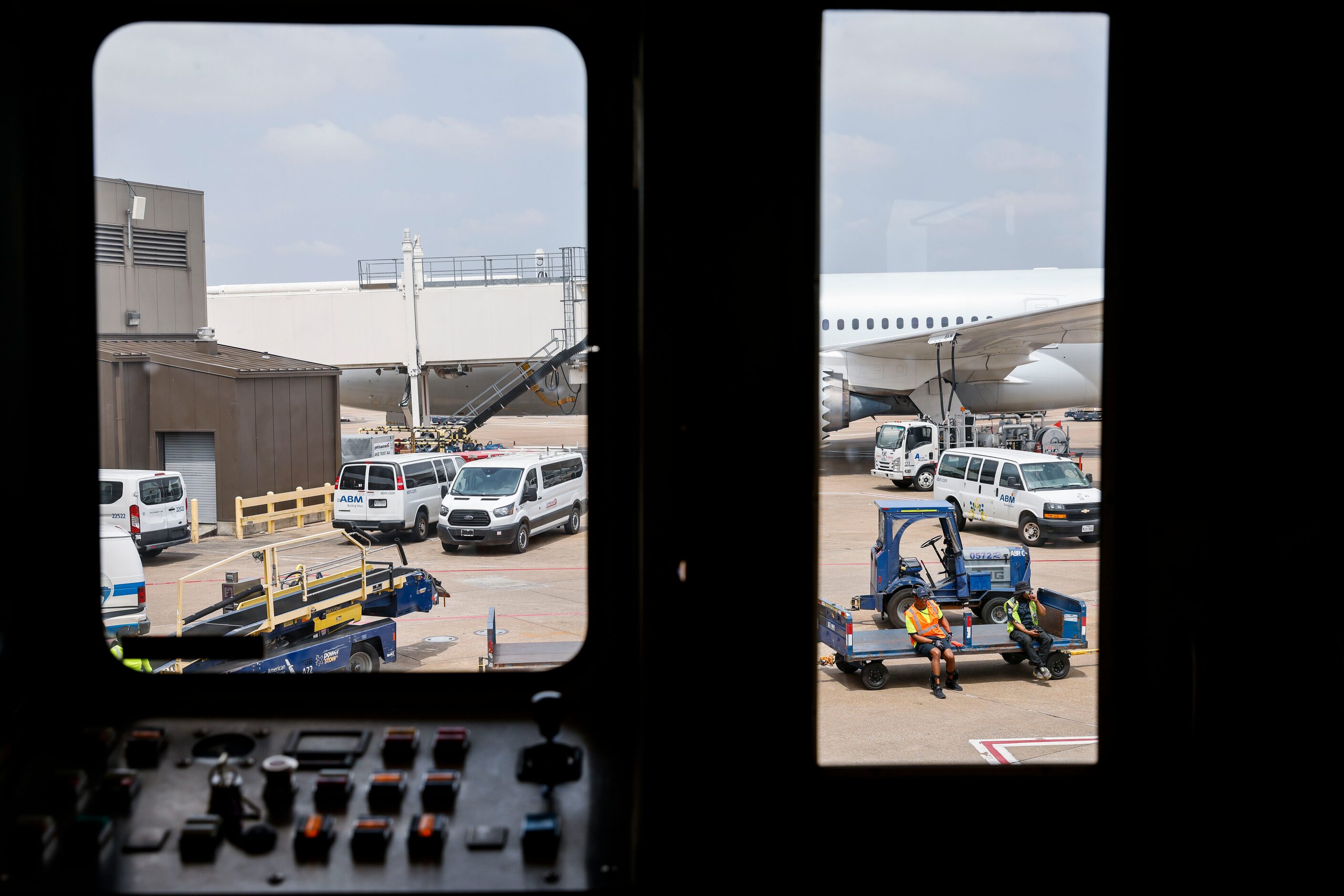 Members of the ground crew are seen through a boarding bridge as they await an American...