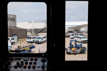 Members of the ground crew are seen through a boarding bridge as they await for an American...