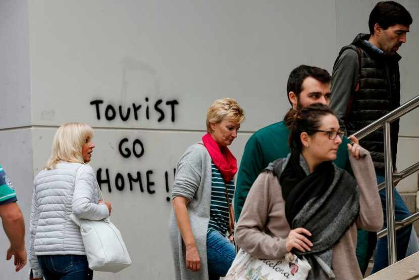Visitors  walked past graffiti reading "Tourist go home!" on their way to Park Guell in...
