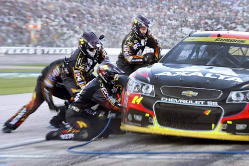 Sprint Cup Series driver Jeff Gordon (24) receives a four-tire change from his crew late in...
