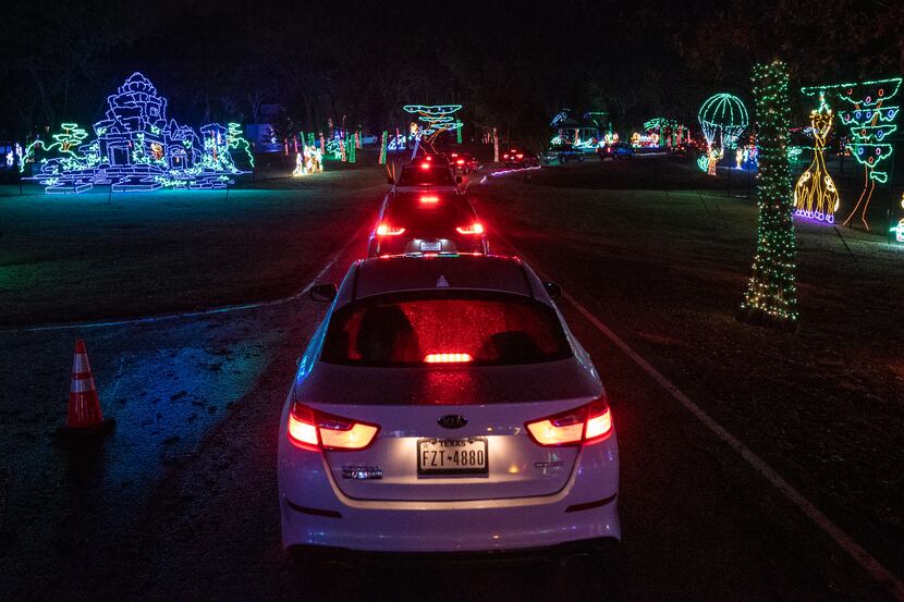 A line of vehicles slowly move through the Christmas Safari section of the Prairie Lights at...