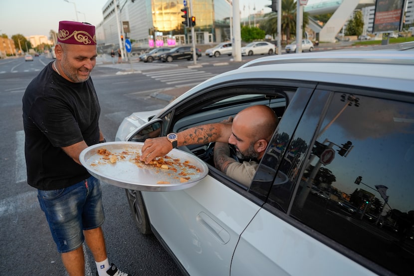 Israeli man Avi Azran distributes sweets to celebrate the news of the death of Hezbollah...