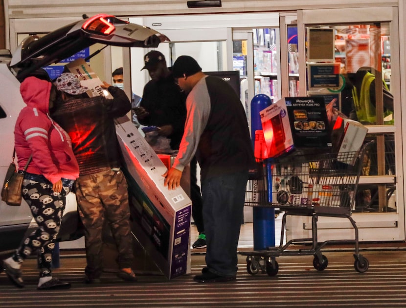 Miriam Rojas. her brother and her husband load a 65-inch TV into the back of their car at...