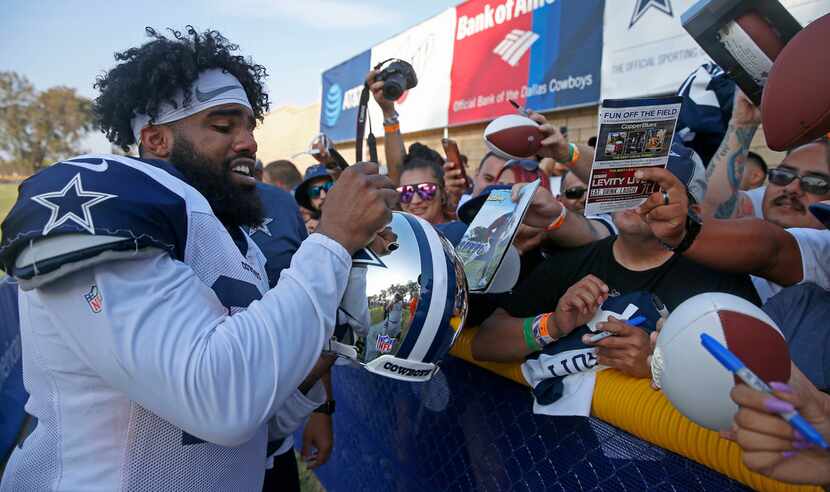 Dallas Cowboys running back Ezekiel Elliott signs autographs for fans after practice at the...