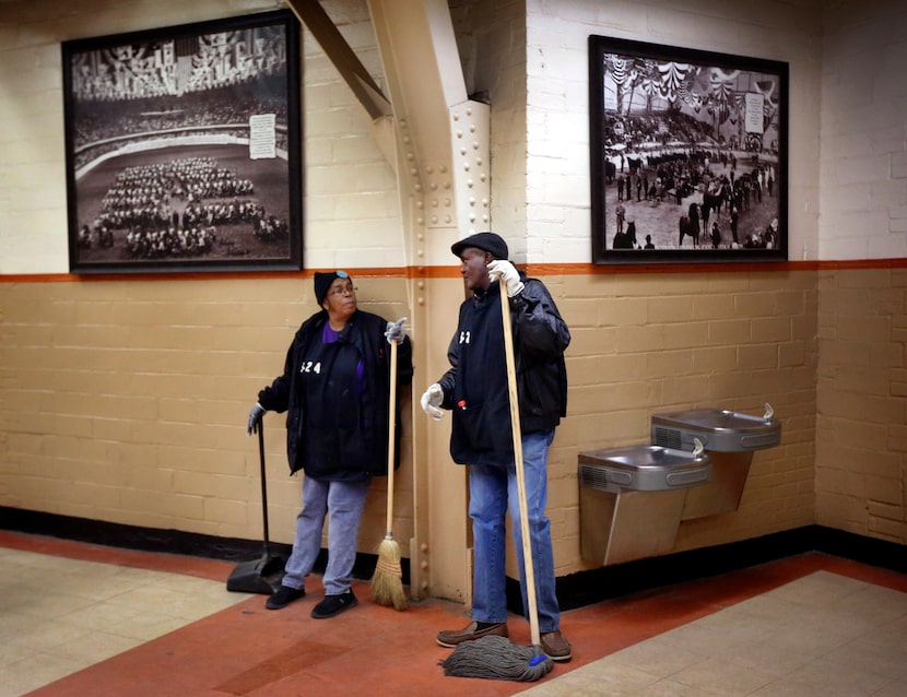 A pair of custodians visit along the historic, photo-lined walls of Will Rogers Memorial...