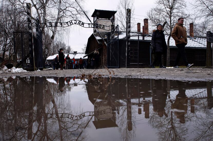 People walk next to the ''Arbeit Macht Frei" (Work Sets You Free) gate at the former Nazi...