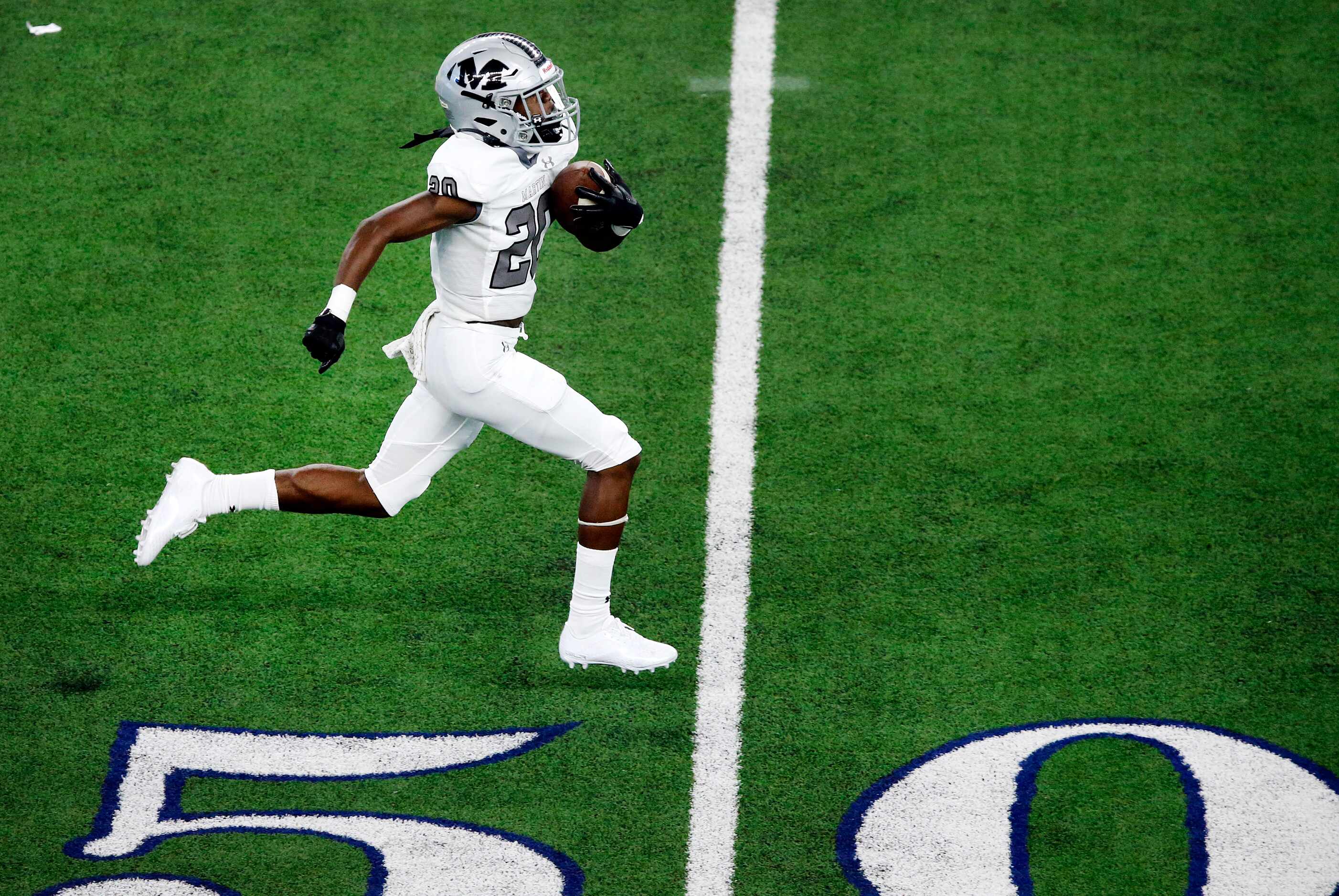 On a blocked extra point, Arlington Martin's Tramell Windham (20) races the length of the...