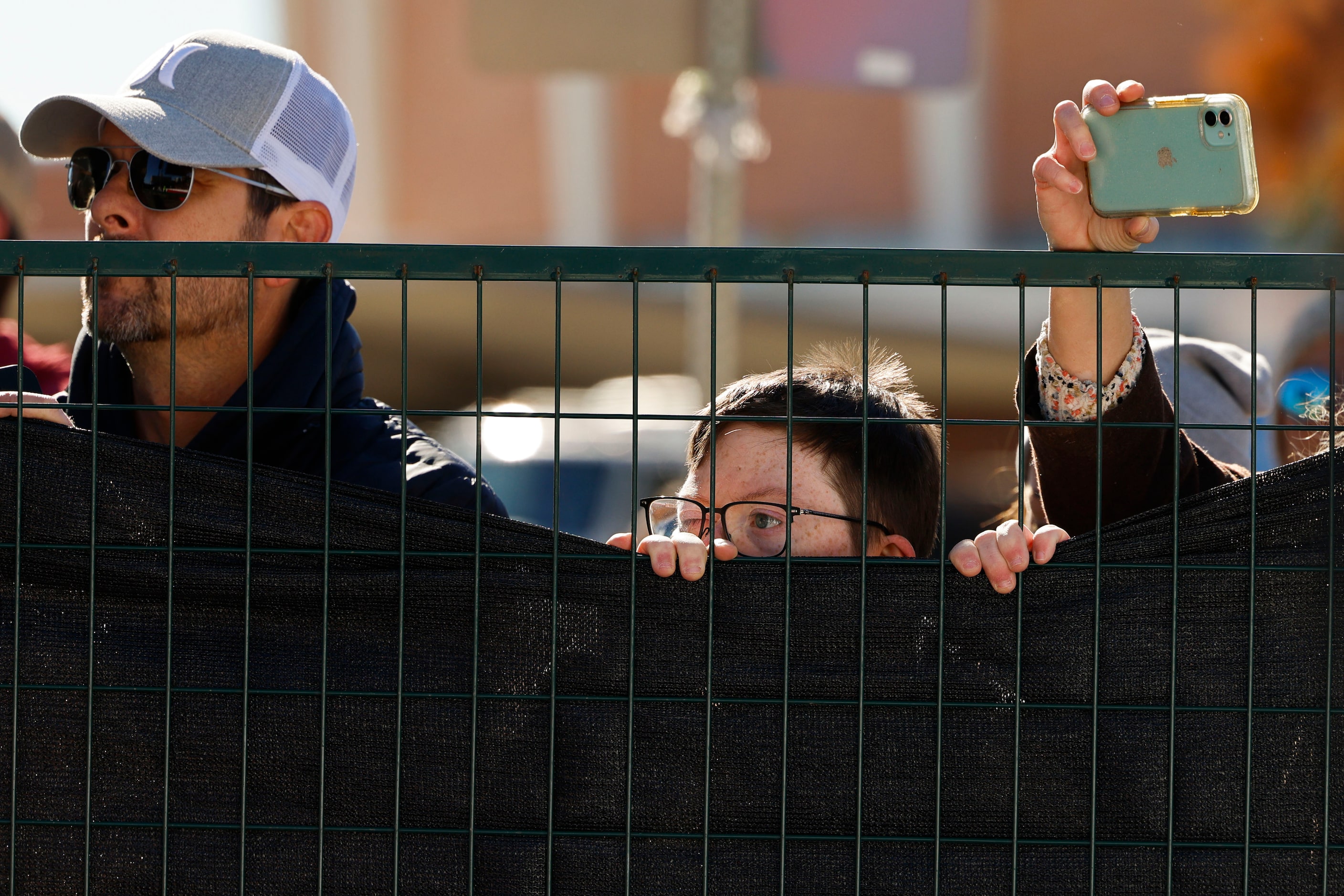 Attending crowd peek through he fence to watch the finish line during 2023 BMW Dallas...