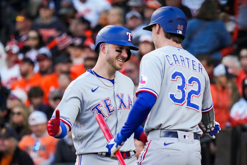 Texas Rangers designated hitter Mitch Garver celebrates with left fielder Evan Carter after...