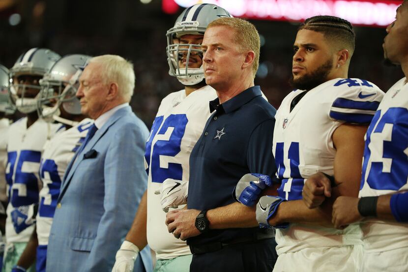 Dallas Cowboys head coach Jason Garrett is locked in arm with teammates before the National...