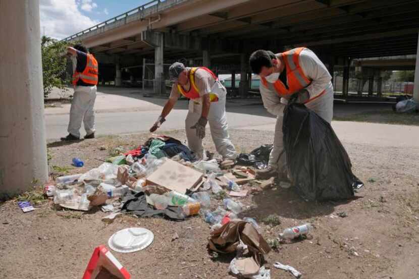 
Workers clean up trash under the overpass. The crisis team’s task can be grueling and...