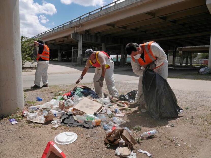 
Workers clean up trash under the overpass. The crisis team’s task can be grueling and...