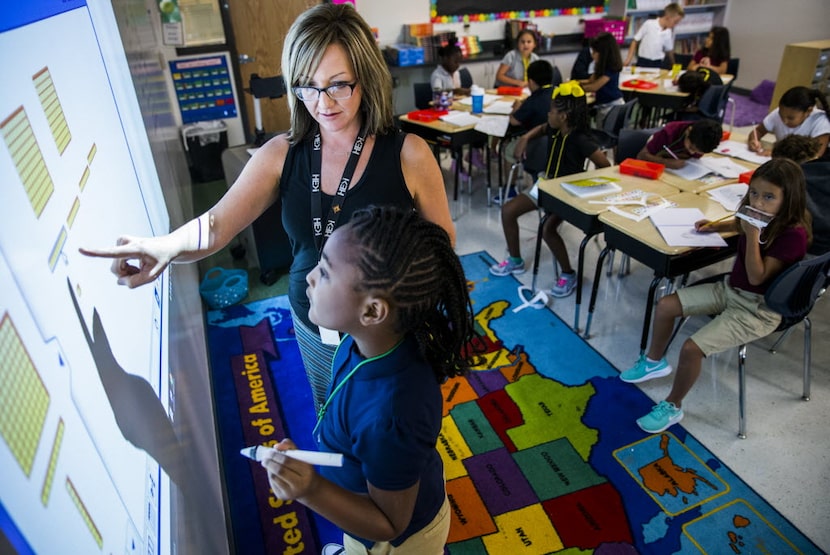 Third-grade teacher Bo Livingston helps Azariyah Shadd, 8, with a math problem on a...