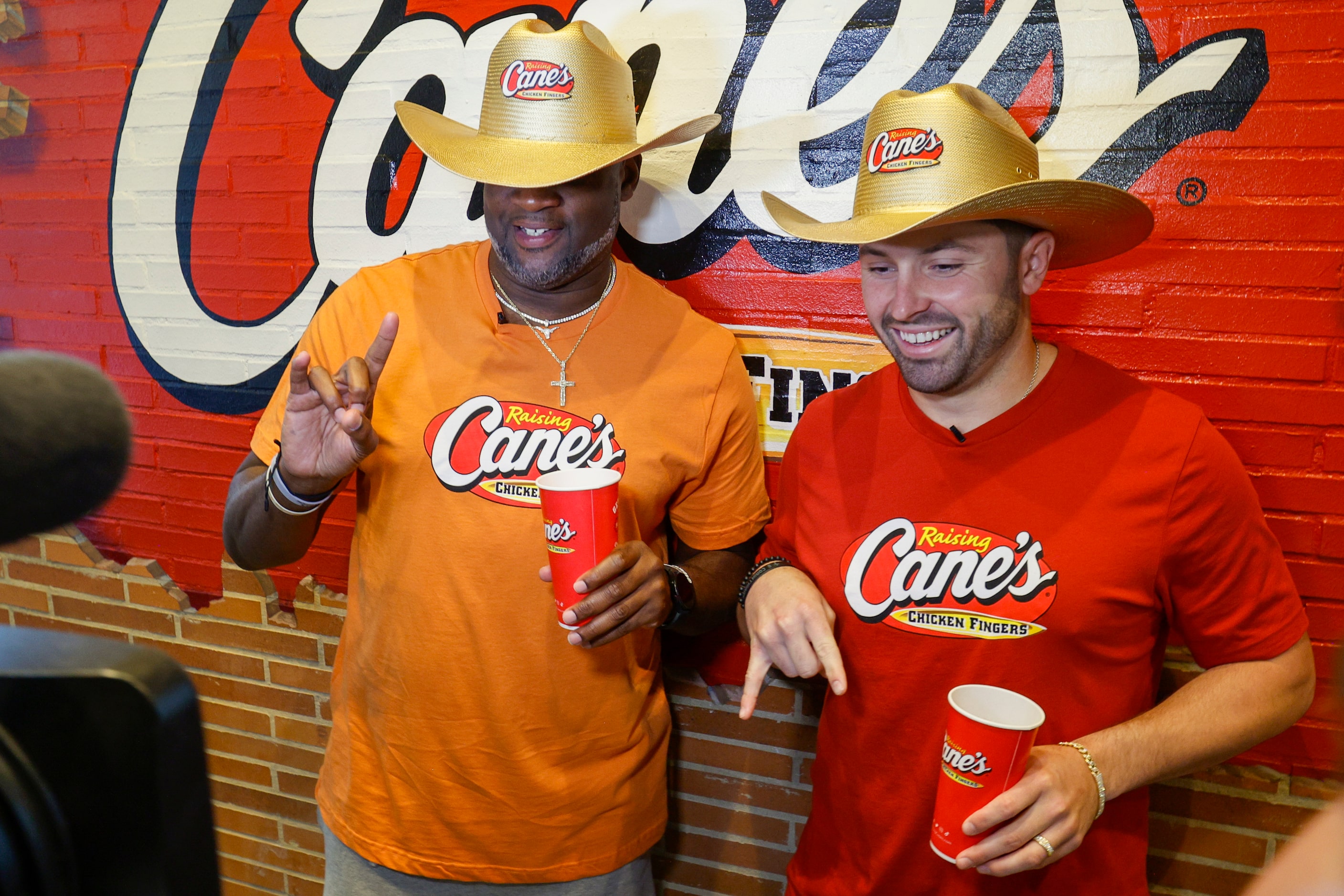 Former Texas quarterback Vince Young (left) holds up the “Hook ‘Em” sign as former Oklahoma...