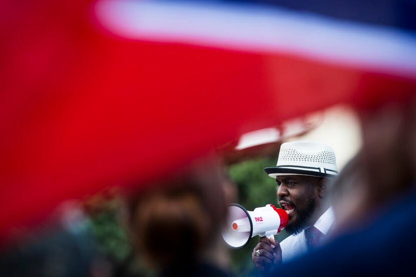 A Confederate flag flies over the shoulder of a counter-protester as Pastor Michael W....