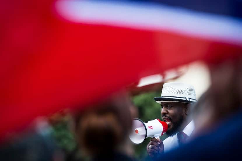 A Confederate flag flies over the shoulder of a counter-protester as Pastor Michael W....