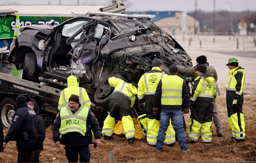 Crews inspect the rear end of a crushed Northlake police SUV as it was loaded onto a flatbed...