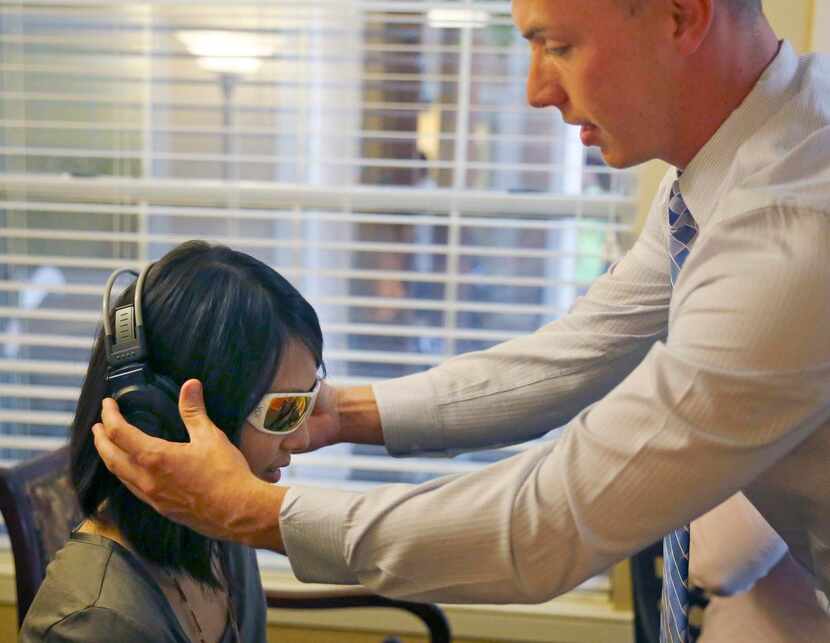 
Russell Christenson places headphones that simulate hearing loss on Wen-Hua Hsieh. “Virtual...