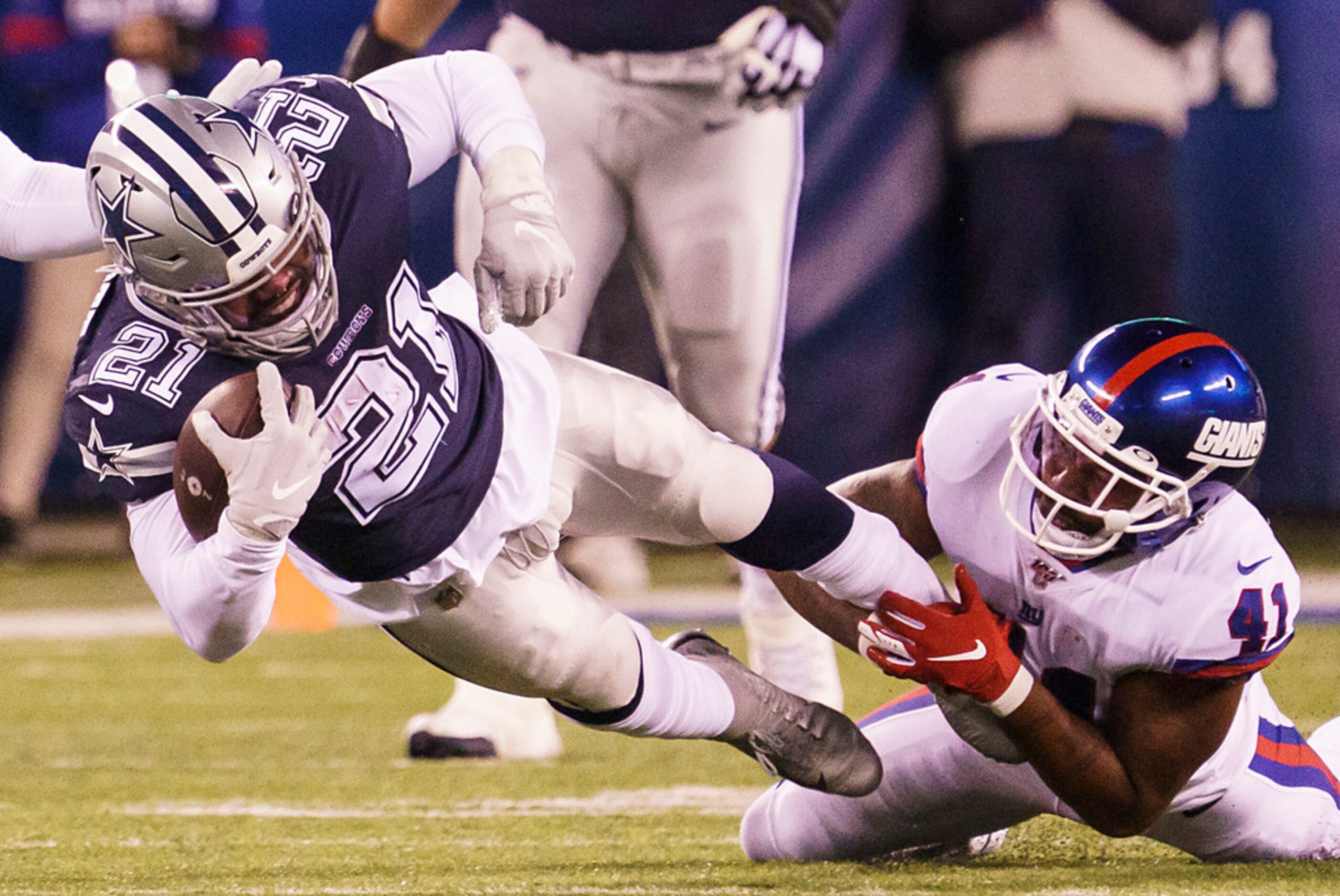 Dallas Cowboys running back Ezekiel Elliott (21) is tripped up by New York Giants free...