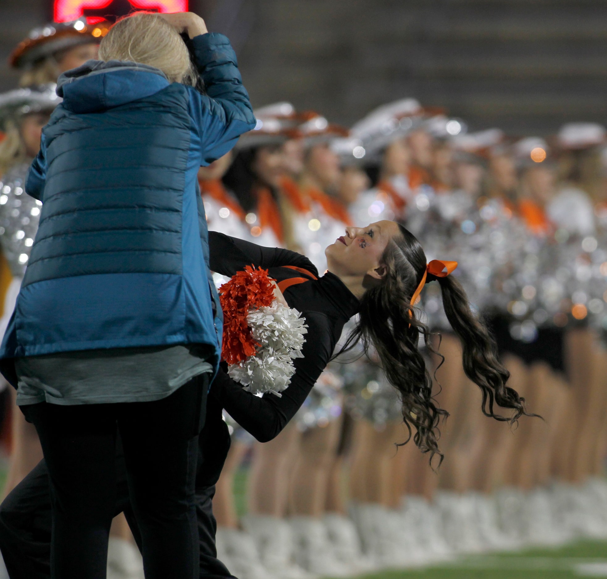 Rockwall senior cheerleader Kaelyn Vaughn, center, works to duck underneath a photographer's...