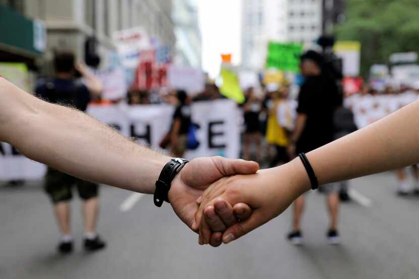 Dos personas se toman la mano en una manifestación en Chicago contra los operativos de la...